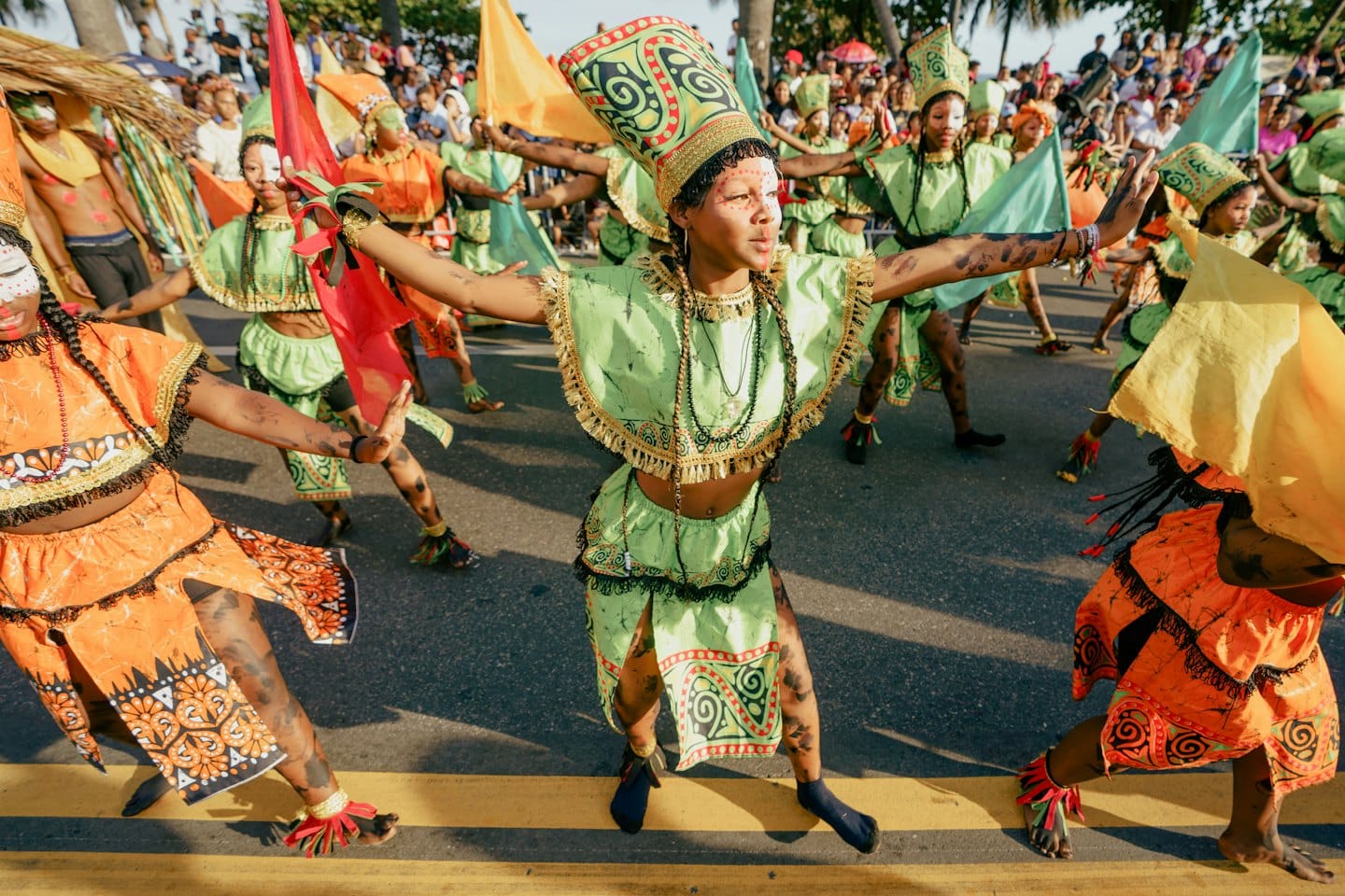 People in colorful costumes dancing in an outdoor street carnival parade.