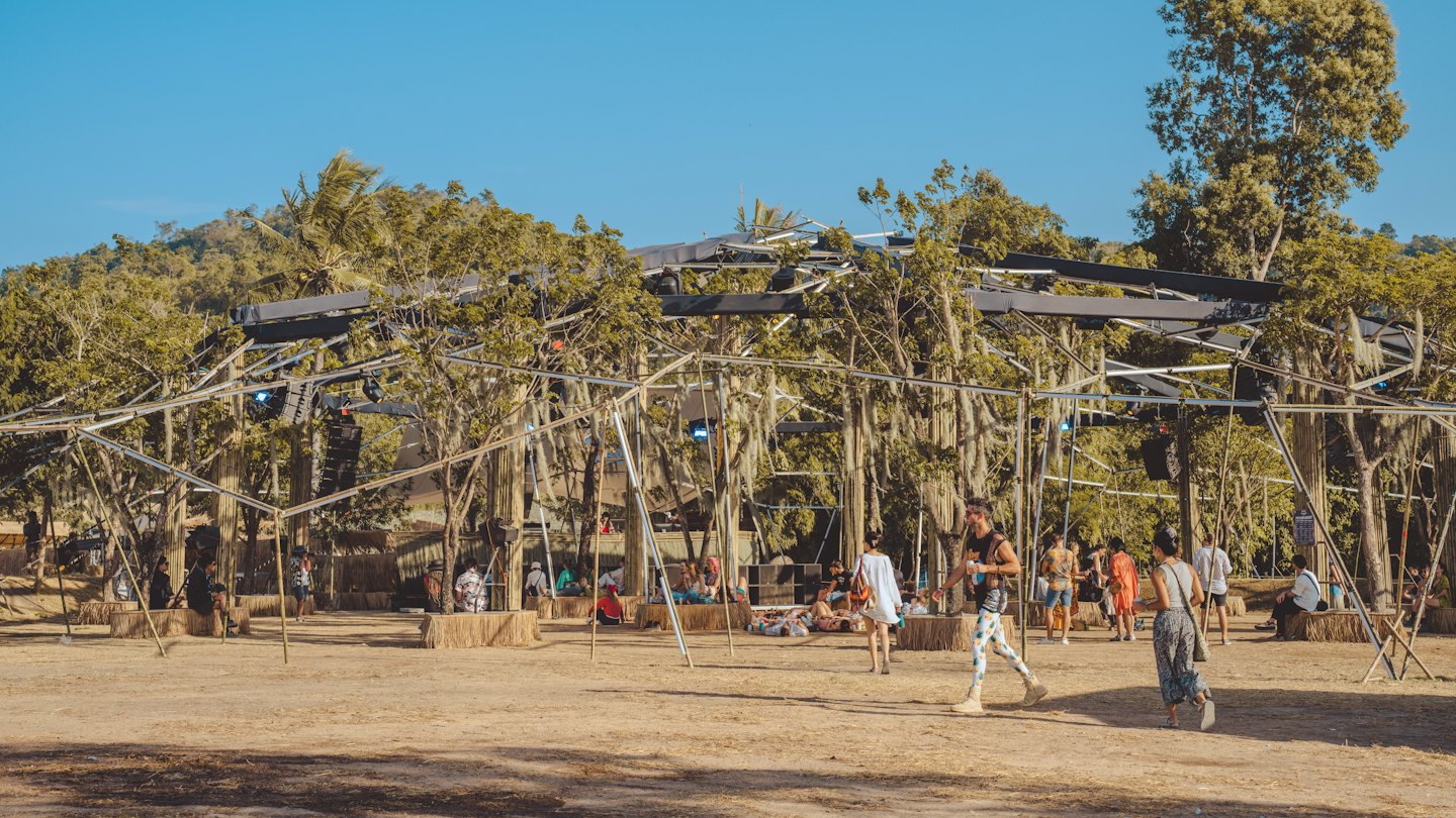 People relax on straw bales at an outdoor music festival.